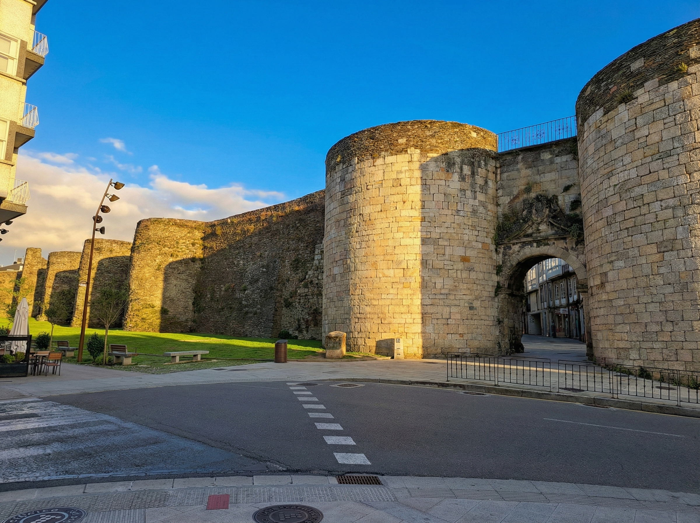 Entrada de la Muralla Romana de Lugo, Patrimonio de la Humanidad. Detalle de los torreones de piedra y el acceso al casco histórico bajo un cielo azul. Alojamiento turístico en el centro de Lugo con Urbe Lucus.